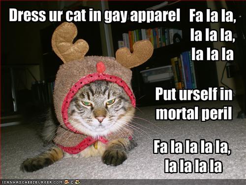 A cat wearing antlers, looking unhappy, captioned "Dress ur cat in gay apparel / fa la la la la la la la la / Put urself in mortal peril / fa la la la la la la la la"