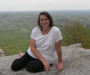 Michelle sitting on a rock ledge at Pretty Place Chapel, with a view of mountains in the background and a valley below