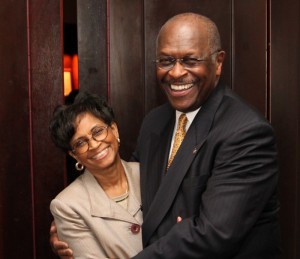 Herman Cain and his wife, smiling and embracing while both looking at the camera