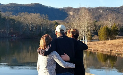 A picture of Joy, Dave, and Michelle as they look out across a lake at Table Rock State Park in South Carolina, with the mountains of the park in the distance
