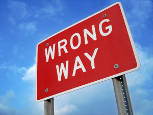 A “Wrong Way” road sign against a blue sky